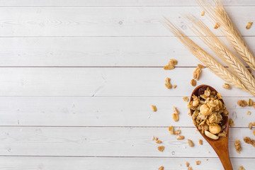 Dry Breakfast of oat flakes, granules and nuts. Muesli on a light table in a wooden spoon and ears. Copy space