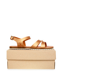 Golden color eco leather sandals with box isolated on white background, copy space template