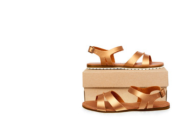 Golden color eco leather sandals with box isolated on white background, copy space template