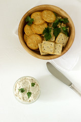 Snack from crackers and curd fish paste with herbs on a light background.