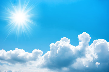 Sun with rays on blue sky with clouds