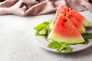 Watermelon sliced on a plate with mint leaves on a wooden background. Copy space