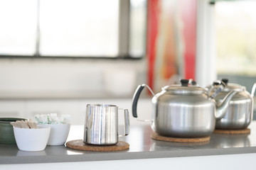 Fototapeta na wymiar Stainless steel kitchenware. Stainless steel set of teapot and pitcher on a counter ready to serve for afternoon tea time.
