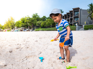 The boy asian two year old toddler playing with beach toys on Hua Hin beach Thailand.