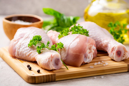 Raw chicken legs with spices and herbs on cutting board