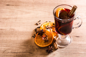 Mulled wine in glass with spice and fruit on wooden table. Copyspace

