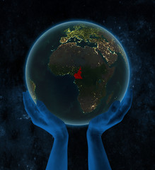Cameroon on night Earth in hands in space