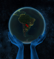 Paraguay on night Earth in hands in space