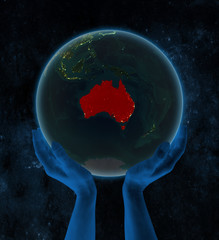 Australia on night Earth in hands in space