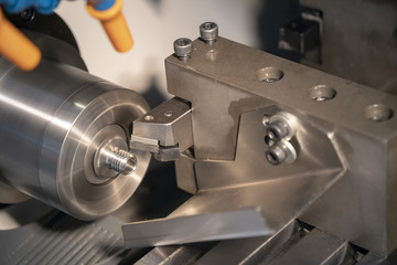 The CNC lathe or turning machine cutting the thread at end of aluminum shaft part.Hi-technology manufacturing process.