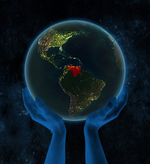 Venezuela on night Earth in hands in space