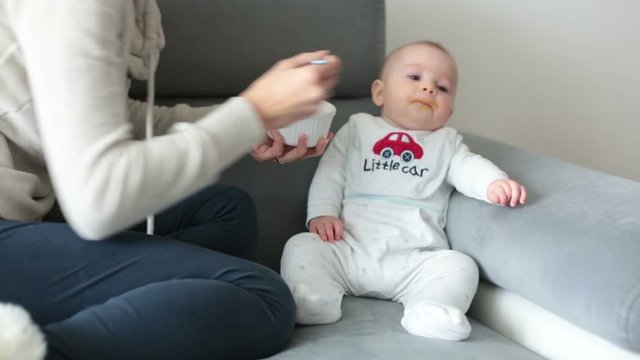 Mother, feeding her baby boy with mashed pumpking for the first time
