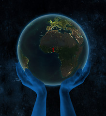 Benin on night Earth in hands in space