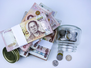 top view over stack of Thai banknote and glass bottle with coins for economy concept