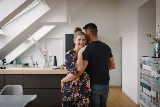 Portrait of pregnant woman standing with her husband at home