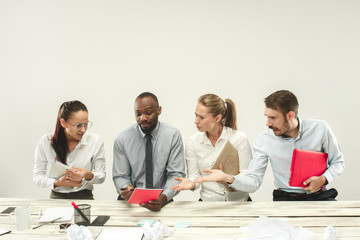 Fototapeta premium Young african and caucasian men and women sitting at office and working on laptops. The business, emotions, team, teamwork, workplace, leadership, meeting concept. different emotions of colleagues