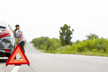 A car breakdown alongside the road, man sets the warning triangle. Driver putting out a traffic warning sign - broken car on the road. man having car trouble on the country road.