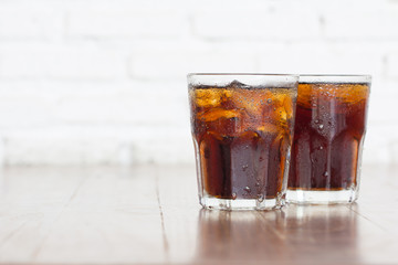 Cool iced soft drink cola  carbonated liquid fresh food with soda water in clear glass on wooden table on white background in restaurant. Double cold soft drink Refreshing brown soda pop flavoured.