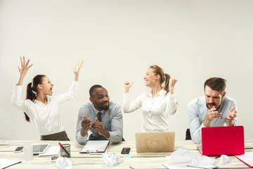 Winners. Young african and caucasian men and women sitting at office and working on laptops. The business, emotions, team, teamwork, workplace, leadership, meeting concept. different emotions of