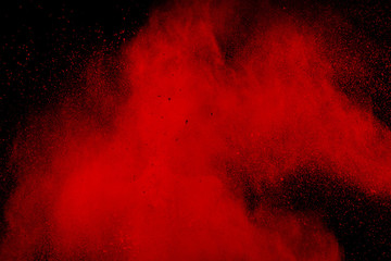 abstract red dust splattered on black background. Red powder explosion.Freeze motion of red...
