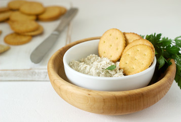 Snack from crackers and curd fish paste with herbs on a light background.