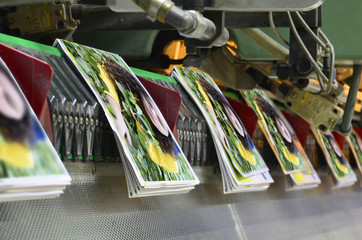 Brochure and magazine stitching process. Close-up of the  offset conveying process of a...