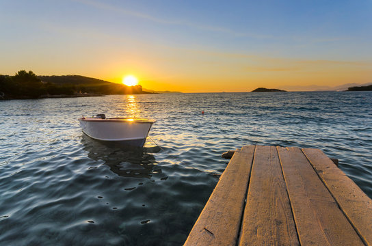 Boat on the pier at sunset on a background of sea and mountains