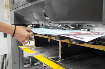Printed paper sheet is pulled by operator on offset print machine