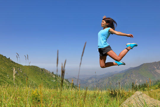 Happy young girl jumping and enjoying life in field