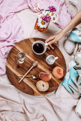 Cozy autumn or winter flatlay of wooden tray with cup of coffee, peaches, creamer with plant milk,...