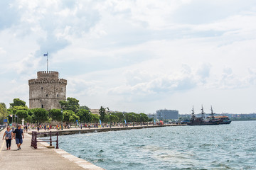 Thessaloniki, Greece - August 16, 2018: White Tower and unidentified people are walking on the embankment in Thessaloniki, Greece.