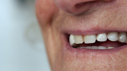 Closeup mouth of elderly woman talking and smiling with perfect teeth