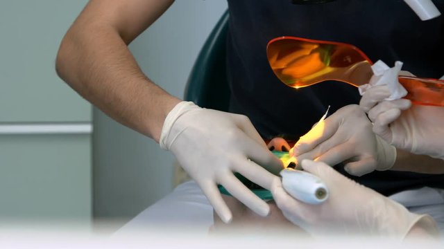Doctor Used Microscope. Dentist Is Treating Patient In Modern Dental Office