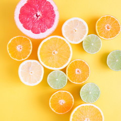 Creative background made of summer tropical fruits, grapefruit, orange, tangerine, lemon, lime on pastel yellow background. Food concept. Flat lay, top view, copy space 