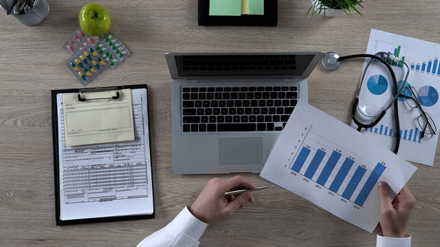 Physician looking at statistics, considering social programs for elderly people - Powered by Adobe