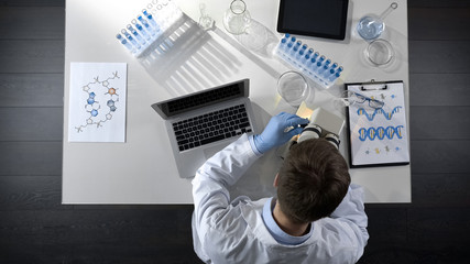 Scientist viewing samples under microscope, research for scientific article