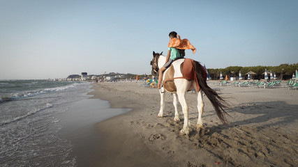 Durres, Albania - circa Aug, 2017: Boy riding horses at seaside on a sunny day. Horses galloping on...