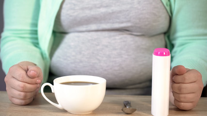 Obese female having tea with sweetener, diabetes diet, fruit-sugar, closeup