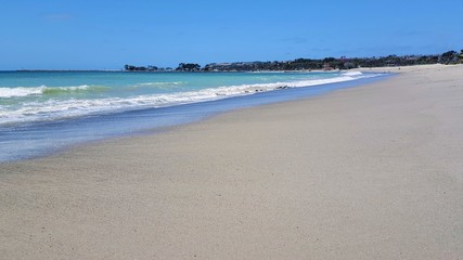 Fototapeta na wymiar Beautiful empty sandy beach with vibrant blue ocean waves.