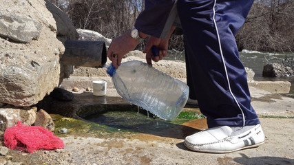 Old man fill plastic bottle with thermal drink water from natural spring