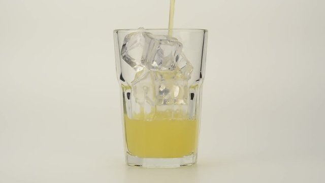 Vertiendo zumo de naranja en un vaso con hielos