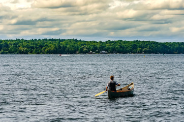 Man canoeing on the St. Lawrence River under a cloudy sky