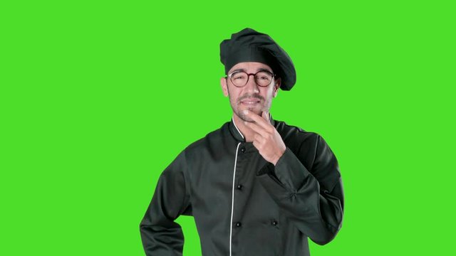 Confident young chef with a gesture of doubt against green background