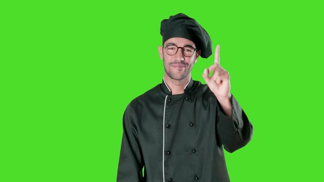 Happy young chef with a gesture of number one against green background
