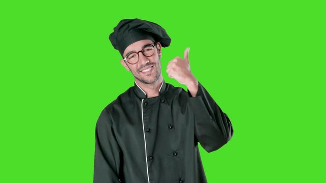 Happy young chef doing an okay gesture against green background