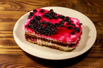 Tasty cheesecake with black currant on wooden table