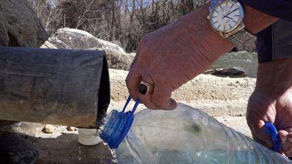 Collecting natural spring water with 5 litre plastic water bottle