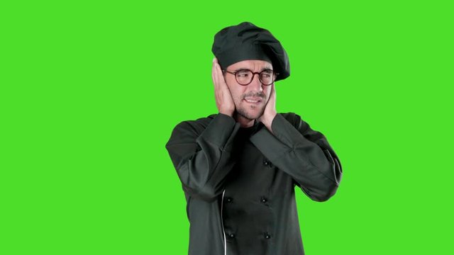 Young chef worried about noise against green background