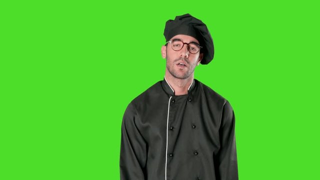 Tired young chef with a boredom gesture against green background