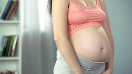 Pregnant woman on third trimester posing for camera, happiness of motherhood